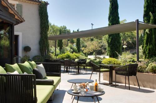 a patio with chairs and tables and an umbrella at Hôtel du Château & Spa - Teritoria in Carcassonne