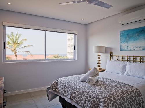 a bedroom with a bed and a large window at Umdloti Holiday Resort Apartments in Umdloti