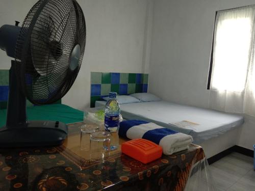 a room with a bed and a table with a fan at The Misty Mountain Guest House in Haldummulla