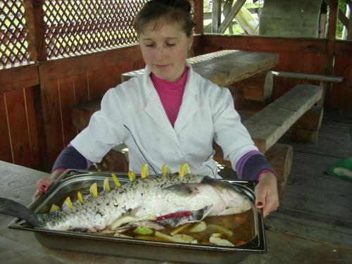 a young girl holding a fish in a tray at Pensiunea Popasul Iancului in Mărişel