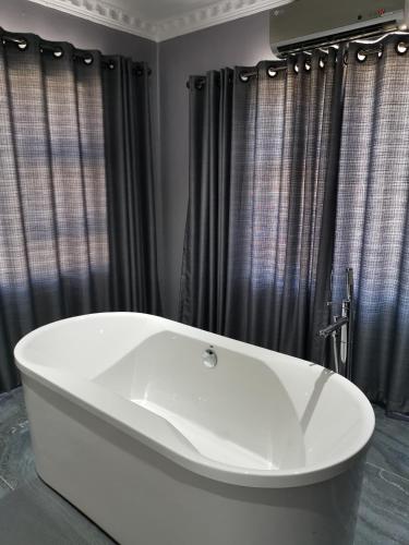 a white bath tub in a bathroom with black curtains at The Green Olive Guesthouse in Bethlehem