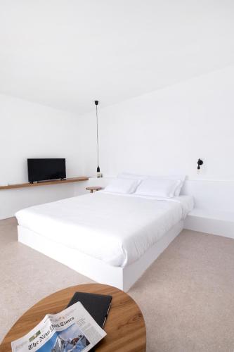 a white bed in a room with a coffee table at Lilium Hotel Santorini in Fira