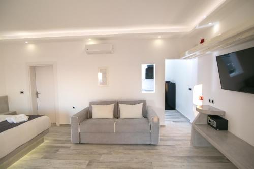 a living room with a couch and a flat screen tv at Aegean Melody Suites & Villas in Vlychada