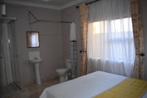 a bedroom with a bed and a toilet and a window at Villa Prince in Harare