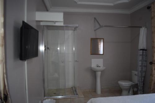 a bathroom with a shower and a toilet and a television at Villa Prince in Harare