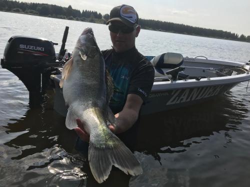 a man holding a large fish in a boat at Kupiškėnų Starkėnas in Palėvenėlė