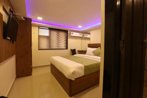 a bedroom with a bed with a purple light at Hotel Happyland in Mumbai