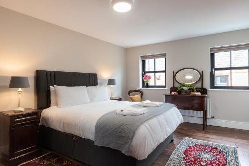a bedroom with a large bed and two windows at Bridge Street Townhouse in Kenmare