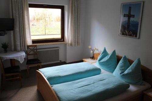 ein Schlafzimmer mit einem Bett mit blauen Kissen und einem Fenster in der Unterkunft Lamplhof B&B in Wiesing