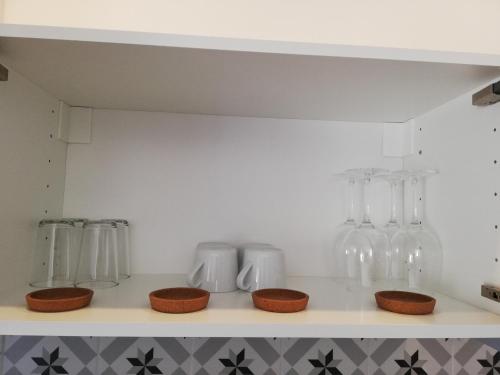 a kitchen with glass bottles and bowls on a shelf at Lopes Apartment - Belch1952 in Lagos