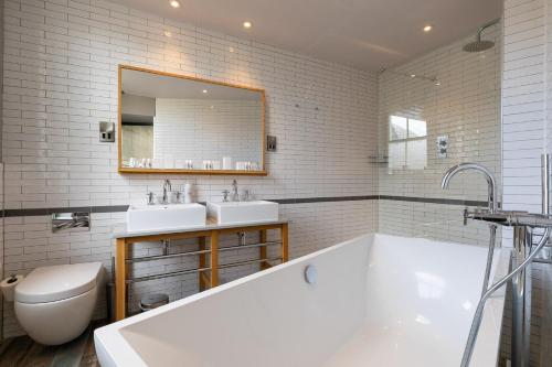 a bathroom with a tub and two sinks and a toilet at The Brook Green Hotel in London