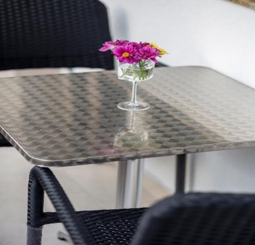 un jarrón de cristal con flores púrpuras sentado en una mesa en Trite Bora Guest House, en Narechenski Bani