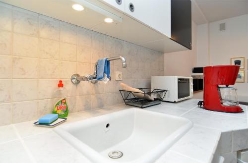 a kitchen with a white sink and a red appliance at House Silvo 1953 in Vodnjan