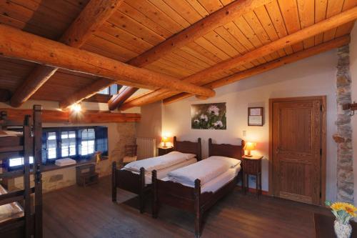 a bedroom with two beds and a wooden ceiling at Albergo Locanda Mistral in Acceglio