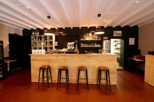 a bar with three bar stools in a restaurant at L'Auberge de Lugos in Lugos