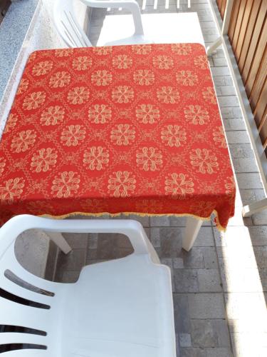 a table with a red table cloth and white chairs at Studio apartman CENTAR in Ogulin