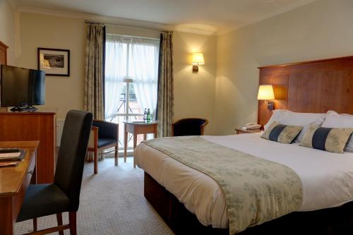 a hotel room with a bed and a desk and a television at Rossett Hall Hotel in Rossett