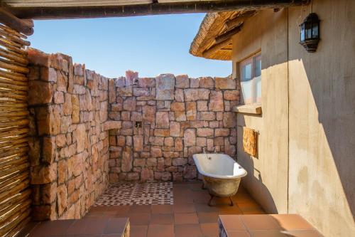 La salle de bains est pourvue d'un mur en pierre et d'une baignoire. dans l'établissement Daberas Guest Farm, à Augrabies