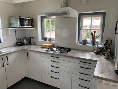 a kitchen with white cabinets and a stove top oven at Erve Feenstra in Lochem