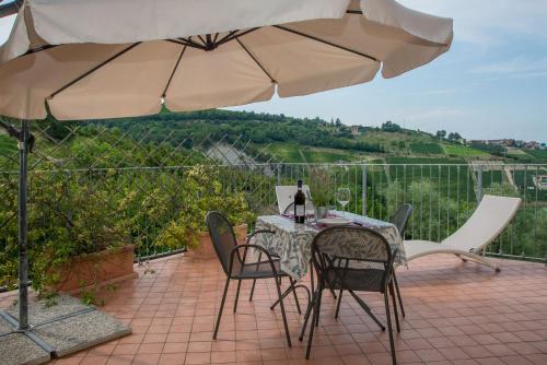 a table and chairs under an umbrella on a patio at Casa Arcobaleno Holiday home apartments in Diano dʼAlba