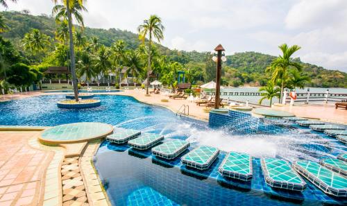 a pool at a resort with chairs and palm trees at Rayong Resort Hotel in Ban Phe