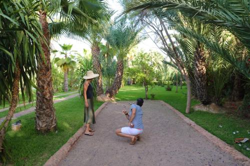 a woman sitting on a bench in front of a palm tree at Villa Le Perroquet Bleu in Marrakech