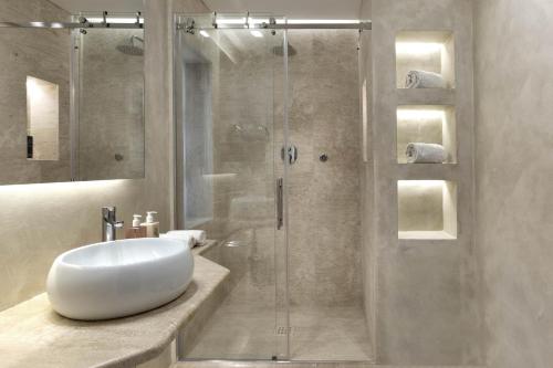 a bathroom with a glass shower with a white sink at Gabbiano Azzurro Hotel & Suites in Golfo Aranci