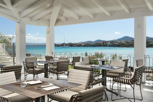 a restaurant with tables and chairs and a view of the water at Gabbiano Azzurro Hotel & Suites in Golfo Aranci