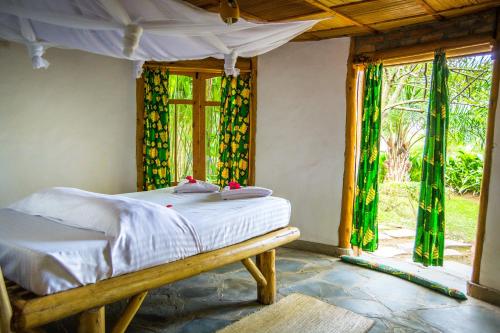 a bedroom with a bed in a room with windows at Paradis Malahide in Gisenyi