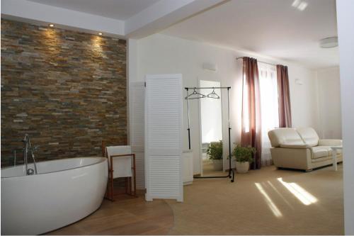 La salle de bains est pourvue d'une baignoire blanche et d'un mur en briques. dans l'établissement Hotel Ambasada, à Krobia
