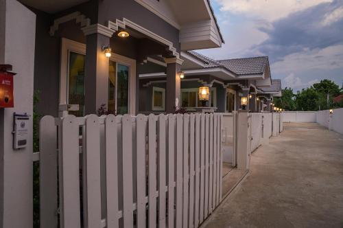 a white fence in front of a house at Chiang Mai Bann Income Homestay in Chiang Mai