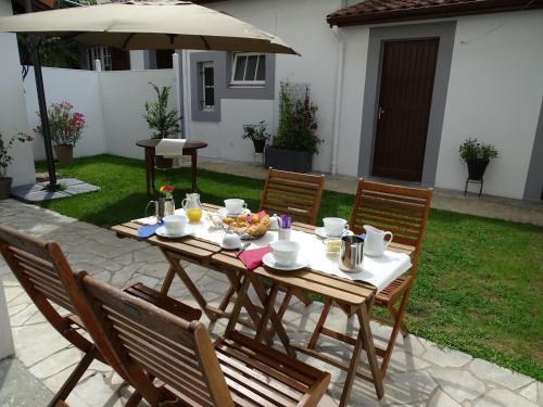 une table en bois avec des chaises et un parasol dans l'établissement A la Vill'Adour, à Dax