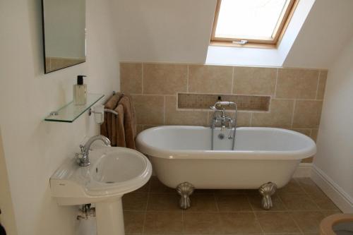 a bathroom with a bath tub and a sink at Thatched Cottage in Hungerford