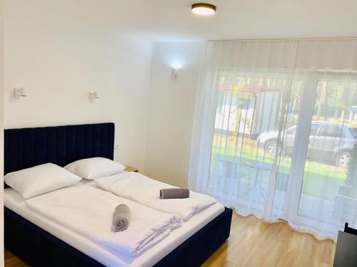 a bedroom with a bed with white sheets and a window at Wojtecki Apartamenty in Pobierowo