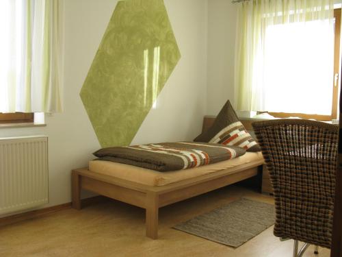 Cama en habitación con silla y ventana en Hefterwaldstüble en Schramberg