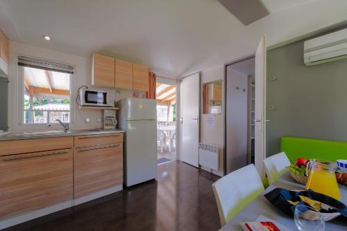 a kitchen with a refrigerator and a table with chairs at Camping Village Mugello Verde in San Piero a Sieve