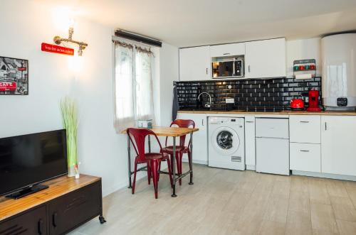 a kitchen with white cabinets and a table with red chairs at Studio Le Perreux proche Paris et Disneyland in Le Perreux-Sur-Marne