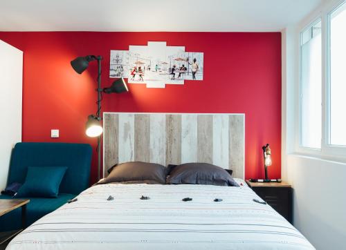 a bedroom with a bed with a red wall at Studio Le Perreux proche Paris et Disneyland in Le Perreux-Sur-Marne