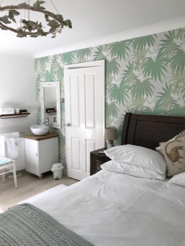 a bedroom with a bed and a bathroom with palm wallpaper at Darceys in the Yard in Hornsea