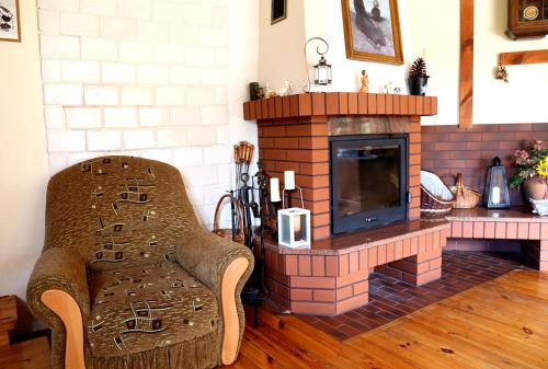 a living room with a fireplace with a chair and a television at Pod Dębem in Giby