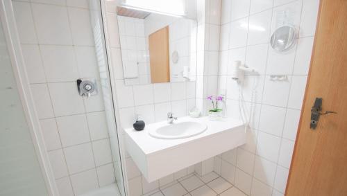 een witte badkamer met een wastafel en een douche bij Hotel Laufelder Hof in Laufeld