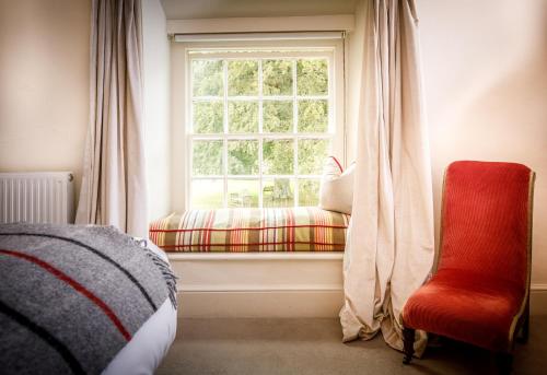a bedroom with a window and a red chair at Trewornan Manor in Wadebridge