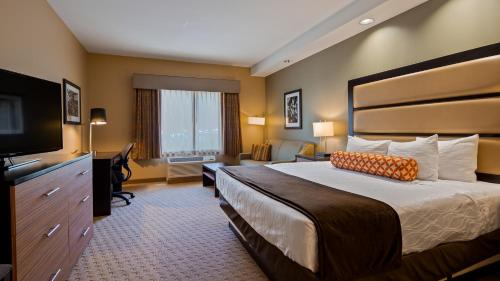 a hotel room with a bed and a flat screen tv at Best Western Plus College Park Hotel in College Park