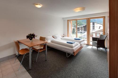 ツェルマットにあるGood Value Apartments by Mountain Exposureのベッド、テーブル、窓が備わる客室です。