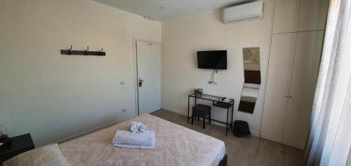 a white room with a bed and a television at Little Rose guest house in Fiumicino