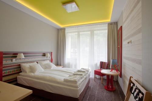 a bedroom with a bed and a table and a window at Hotel Piwniczna SPA&Conference in Piwniczna