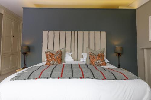 a bedroom with a large white bed with orange and gray pillows at Trewornan Manor in Wadebridge