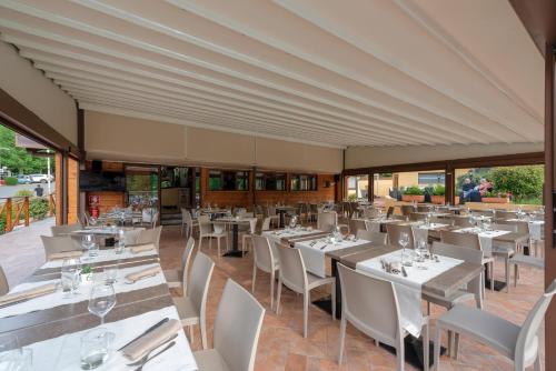 um restaurante com mesas e cadeiras brancas e janelas em Camping Village Mugello Verde em San Piero a Sieve