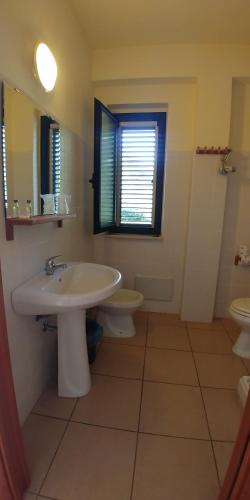 ein Bad mit einem Waschbecken, einem WC und einem Fenster in der Unterkunft La Piana degli Ulivi in Rossano