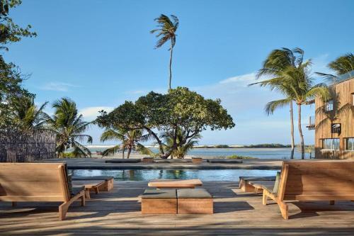 a pool with benches and palm trees and water at CasaMar Guriú in Guriú